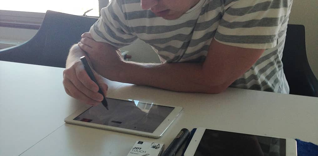 Designer sketching with an Adonit stylus on an iPad at a conference room table