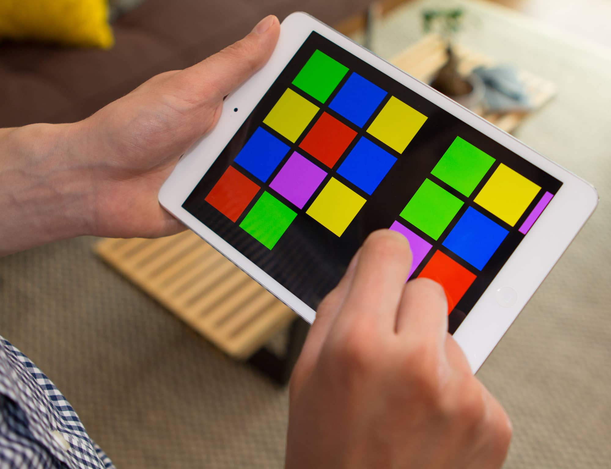 Man using prototype on an iPad to sort and group brightly colored squares on the screen