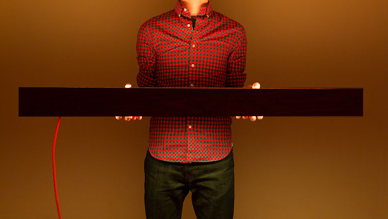 A man holding the BarLight at waist height as the light illuminates the room in a soft orange color